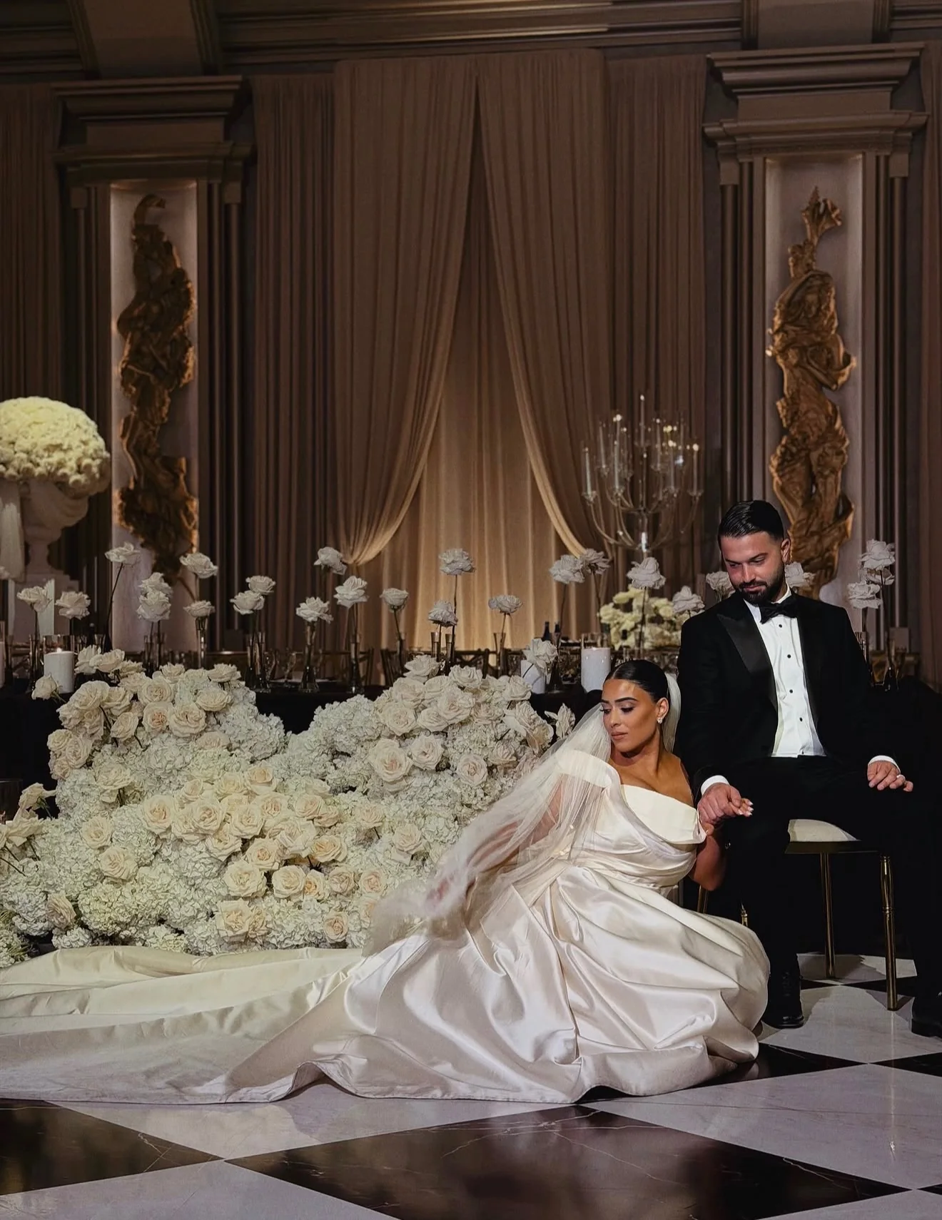 A newly married couple seated among abundant white flowers